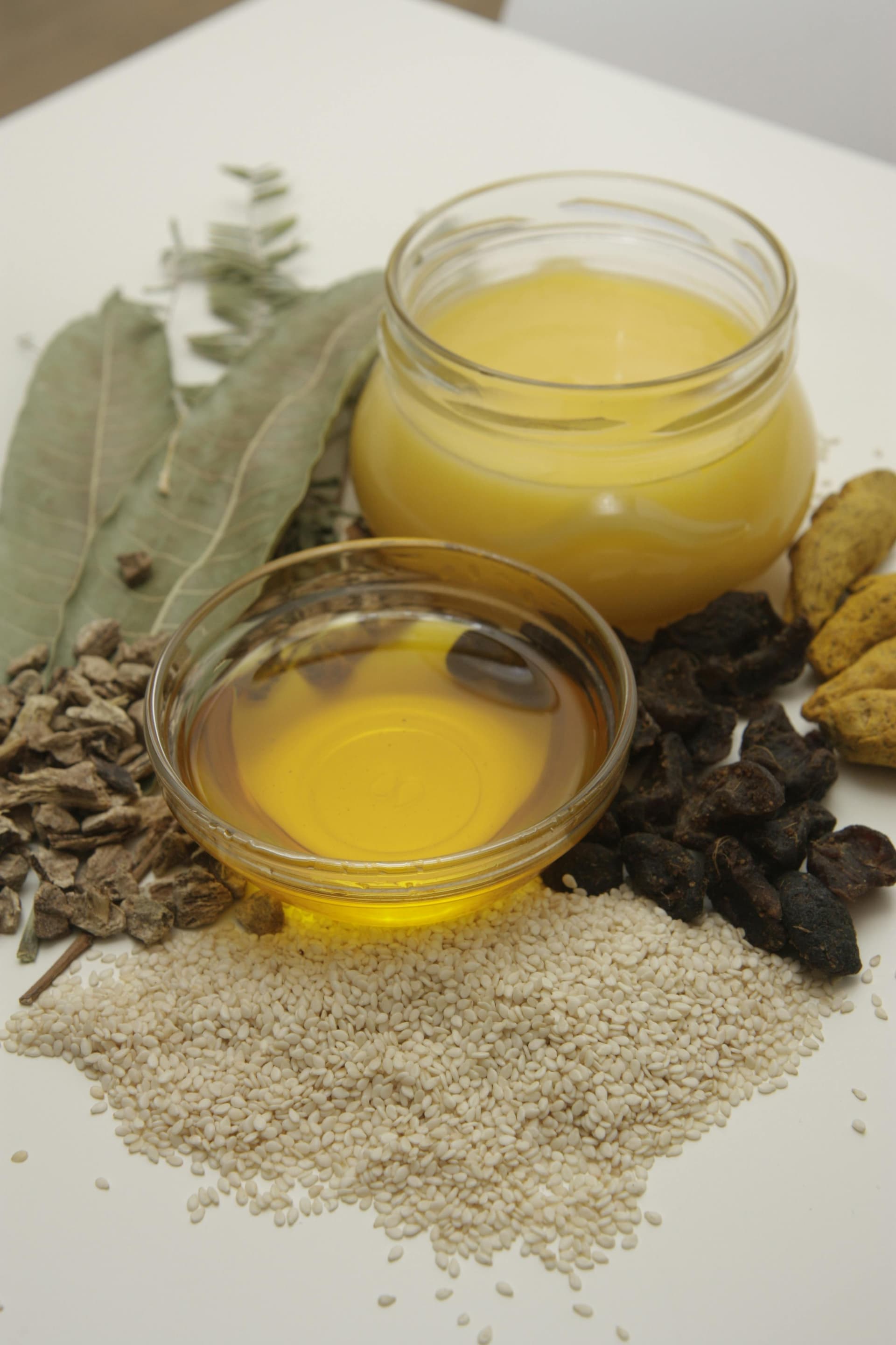 Glass jars of fresh Ayurvedic herbs and powders on a wooden shelf.